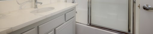 A white bathroom with a sink, mirror, and shower.