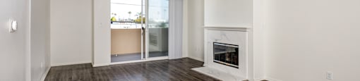 A large, empty room with a fireplace and wooden floors.