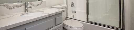 A white bathroom with a toilet, sink, and shower.