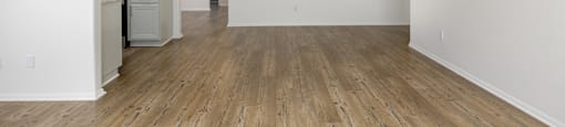 an empty living room and kitchen with white walls and wood flooring