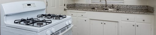a kitchen with white appliances and granite counter tops and white cabinets