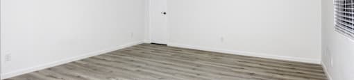 an empty room with white walls and wood floors