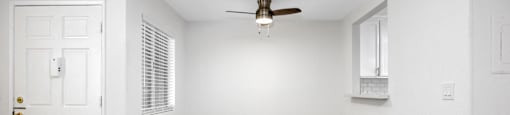 an empty room with white walls and a ceiling fan