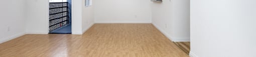 an empty living room with wood floors and white walls