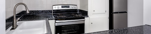 A kitchen with a black granite countertop and white cabinets.