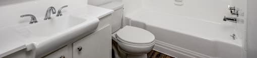 A white bathroom with a toilet, sink, and bathtub.