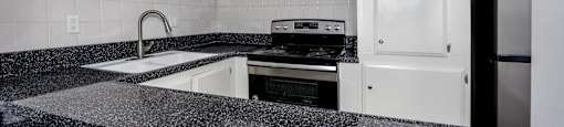A kitchen with white cabinets and a black granite countertop.