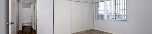 A room with a carpeted floor and a window with blinds.