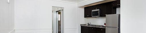 an empty room with white walls and a kitchen with stainless steel appliances
