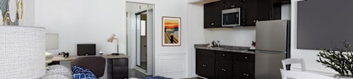 a bedroom with a bed and a kitchen with a refrigerator