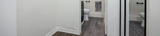 a small bathroom with white walls and wood floors and a toilet
