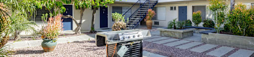 a patio with a grill and a building with a staircase