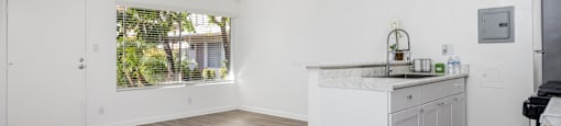 an empty kitchen and living room with white walls and wood floors