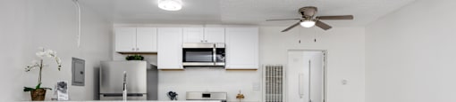 an open kitchen and living room with a counter top and a ceiling fan