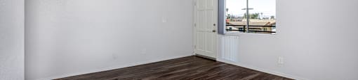 Empty room with wooden flooring and a window.