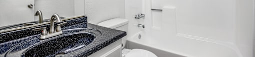 A bathroom with a black granite countertop and white fixtures.