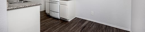 A kitchen with white cabinets and a wood floor.