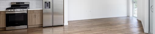 a kitchen with white walls and wooden floors and stainless steel appliances
