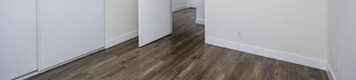 an empty bedroom with white walls and wood flooring
