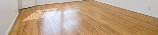 an empty living room with wood floors and a window