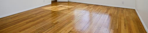 an empty living room with wood floors and a window