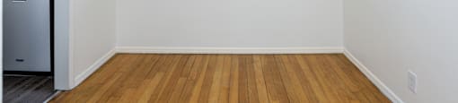 an empty living room with a window and a kitchen