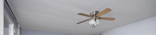 A room with a ceiling fan and wooden flooring.