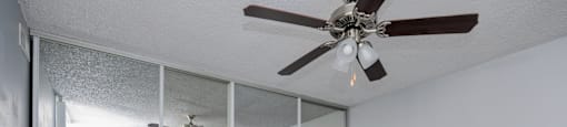 A room with a ceiling fan and sliding glass doors.