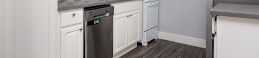 A kitchen with white cabinets and a black dishwasher.
