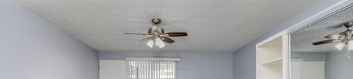 A room with a ceiling fan and a sliding door.