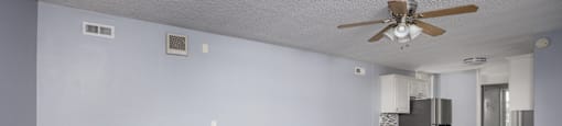 A room with a ceiling fan and a refrigerator.