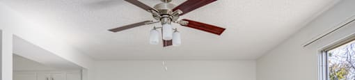 an empty living room with a ceiling fan and a kitchen