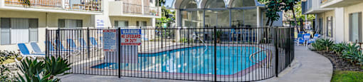 a swimming pool is behind a fence in front of an apartment building