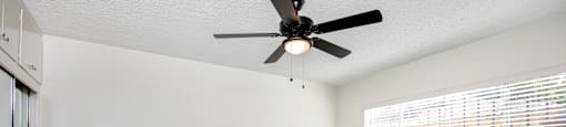 A room with a ceiling fan and wooden flooring.