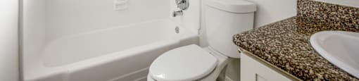 A white bathroom with a toilet, sink, and bathtub.