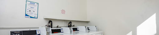 A row of white front loading washing machines in a laundromat.