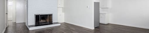 A room with a fireplace and wood flooring.