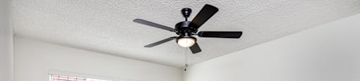 A room with a ceiling fan and a window with blinds.