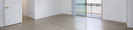 an empty living room with wood floors and a balcony