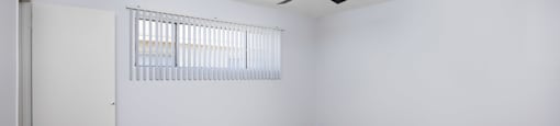 A room with a ceiling fan and a window with blinds.