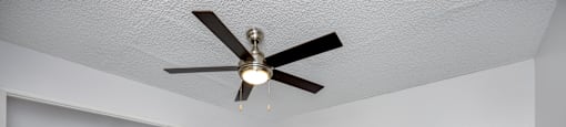 A room with a ceiling fan and carpeted floor.