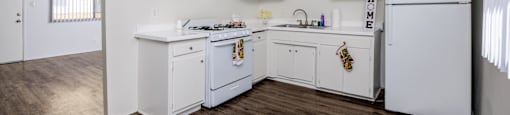 A kitchen with white cabinets and a wooden floor.