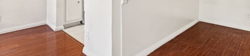 A white wall with a brown floor and a white cabinet.