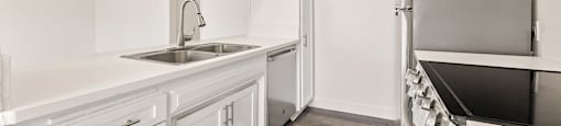 A kitchen with white cabinets and a sink.