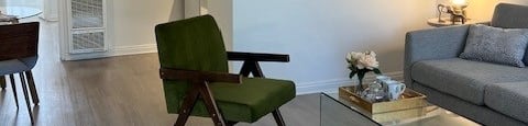 A living room with a green chair and a glass coffee table.