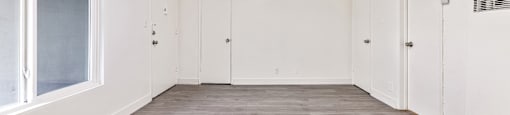 A room with a window, two doors, and a vent on the wall.