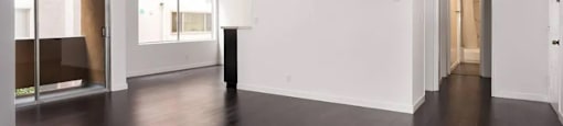 A room with white walls and dark wood flooring.