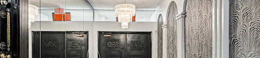 A hallway with black doors and a chandelier hanging from the ceiling.