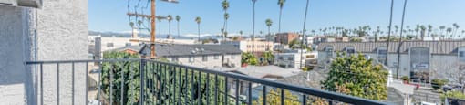 a balcony with a view of the city and palm trees