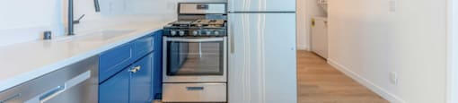 A kitchen with blue cabinets and stainless steel appliances.